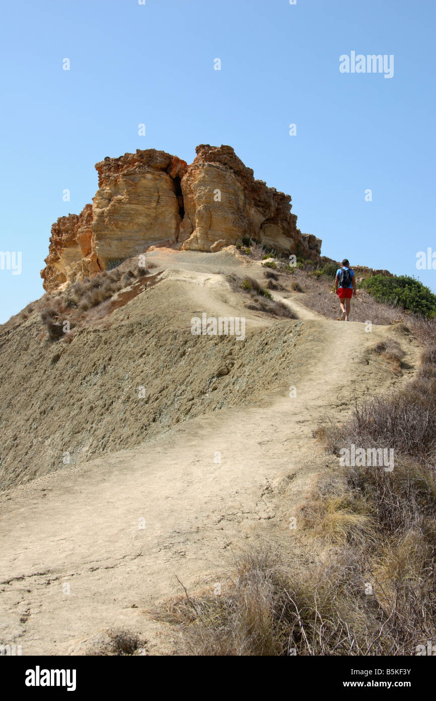 Un uomo a piedi fino ai rocciosi clifftop percorso in corrispondenza di 'Ghajn Tuffieha Bay', Malta. Foto Stock