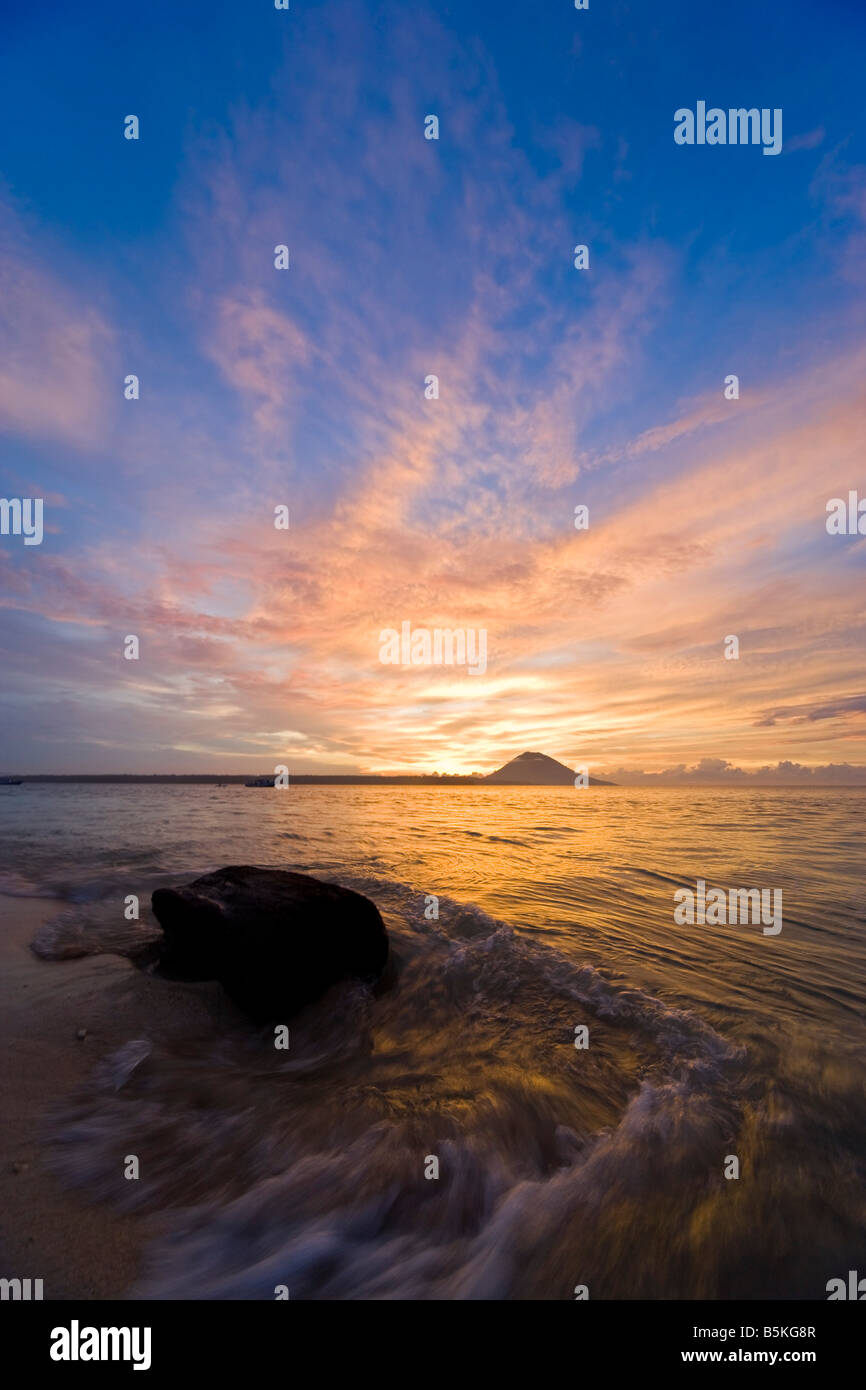 Tramonto tropicale - onde rotoli sulla spiaggia può essere visto in primo piano. Foto Stock