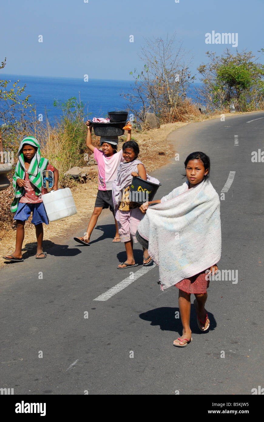 Bambini Balinese sono in corso di avere doccia e ottenere acqua di casa,Amed, Bali, Indonesia Foto Stock