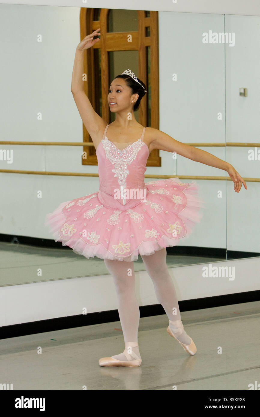 Bambina ballerina in un tutù rosa e scarpe da punta in posa in uno studio  bianco