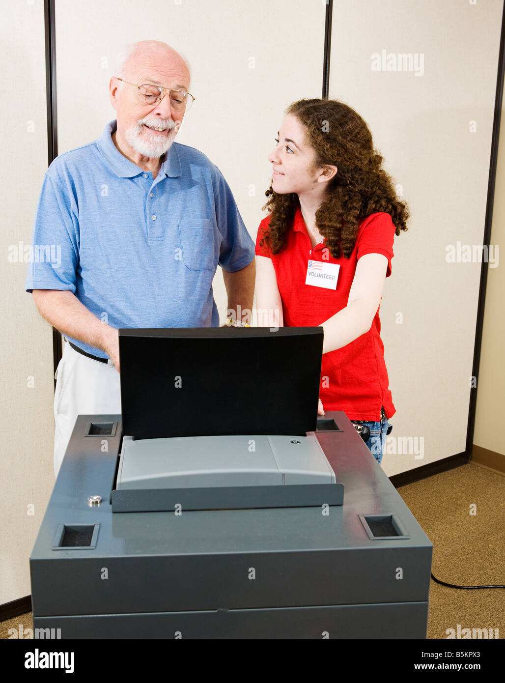 Volunteer spiega nuova scansione ottica macchina di voto a un senior il giorno delle elezioni Foto Stock