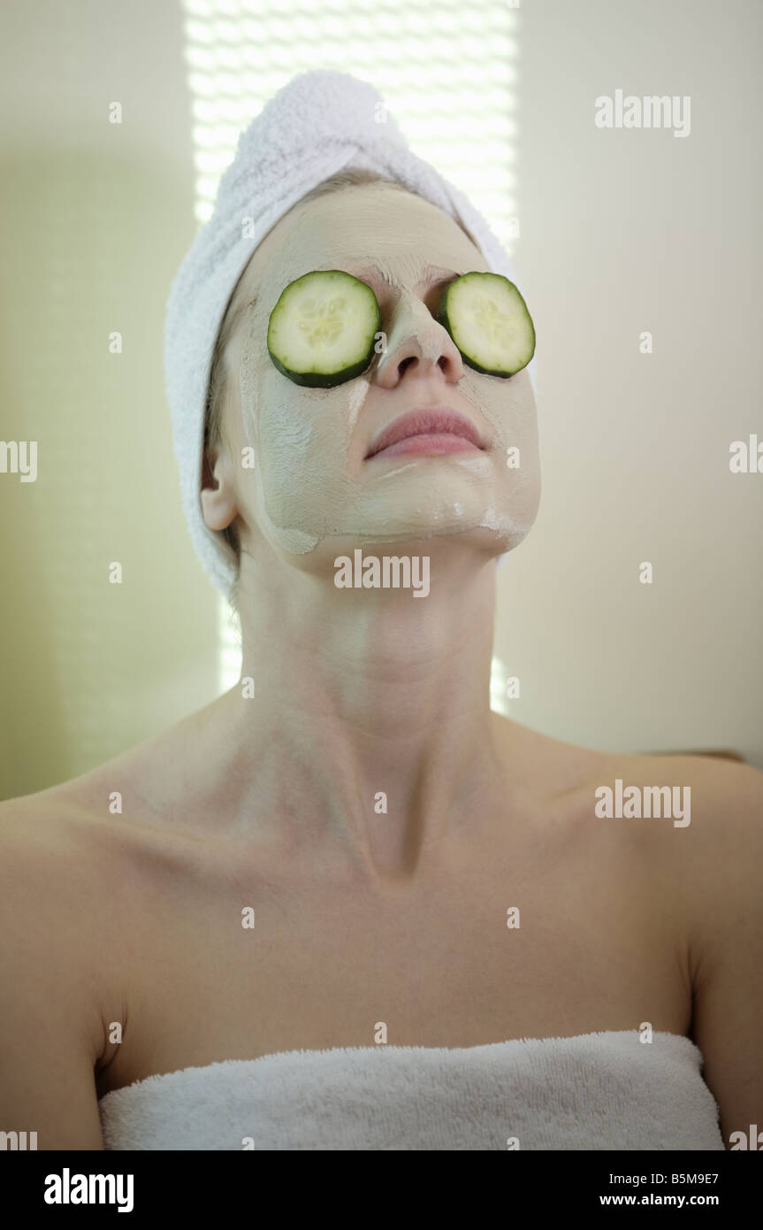 Donna di ottenere un trattamento del viso con cetrioli su i suoi occhi. Foto Stock