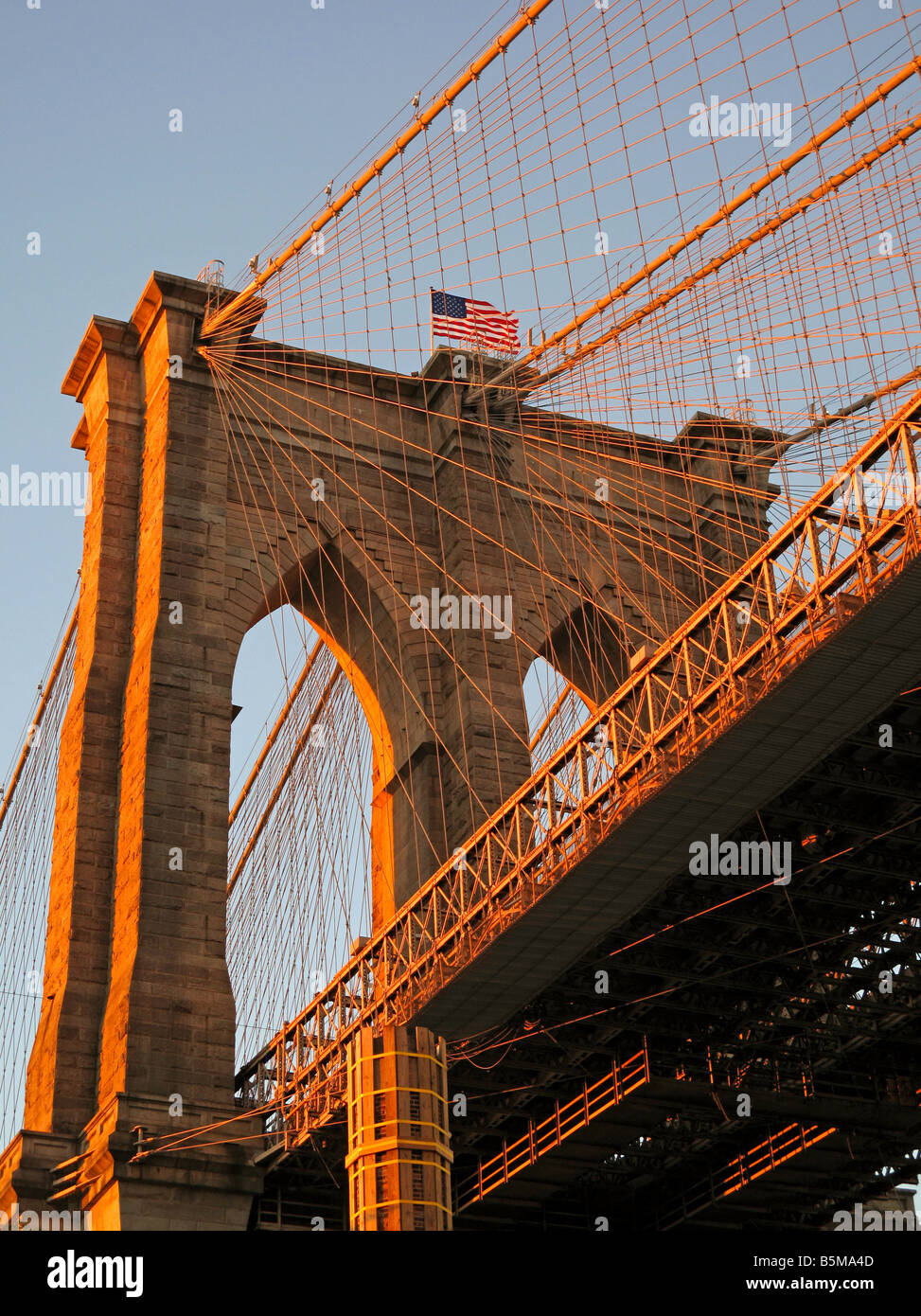 Ponte di Brooklyn cercando fino al tramonto bandiera americana Foto Stock