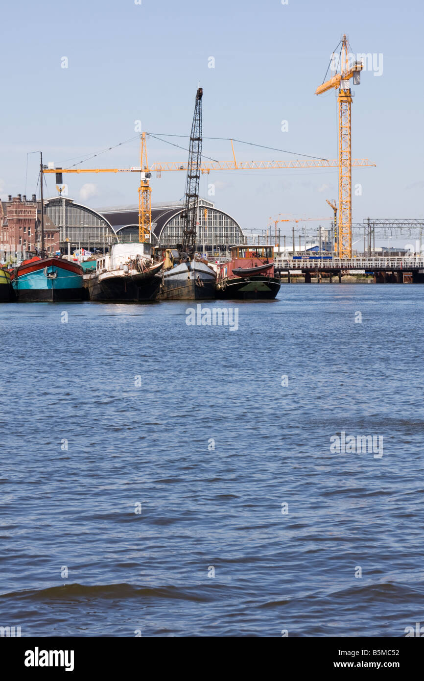 Amsterdam Oosterdok - Imbarcazioni, gru e la stazione centrale di Amsterdam Foto Stock