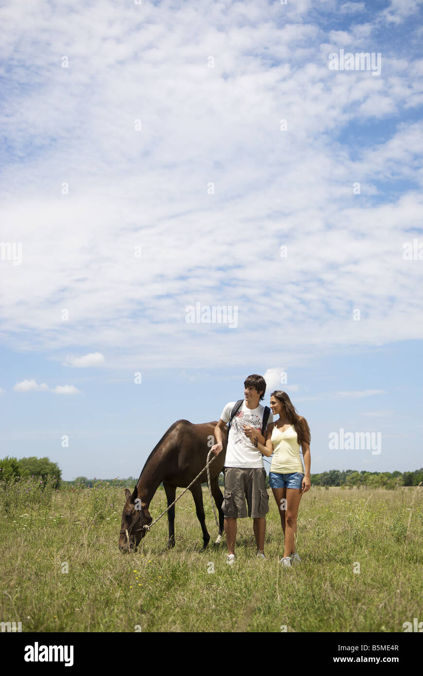 Una coppia in un pascolo con un cavallo Foto Stock