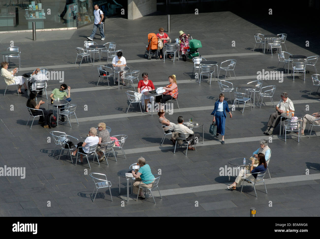 Le persone sedute a tavoli all aperto a Londra il South Bank prima del Teatro Nazionale di Londra, Inghilterra Foto Stock