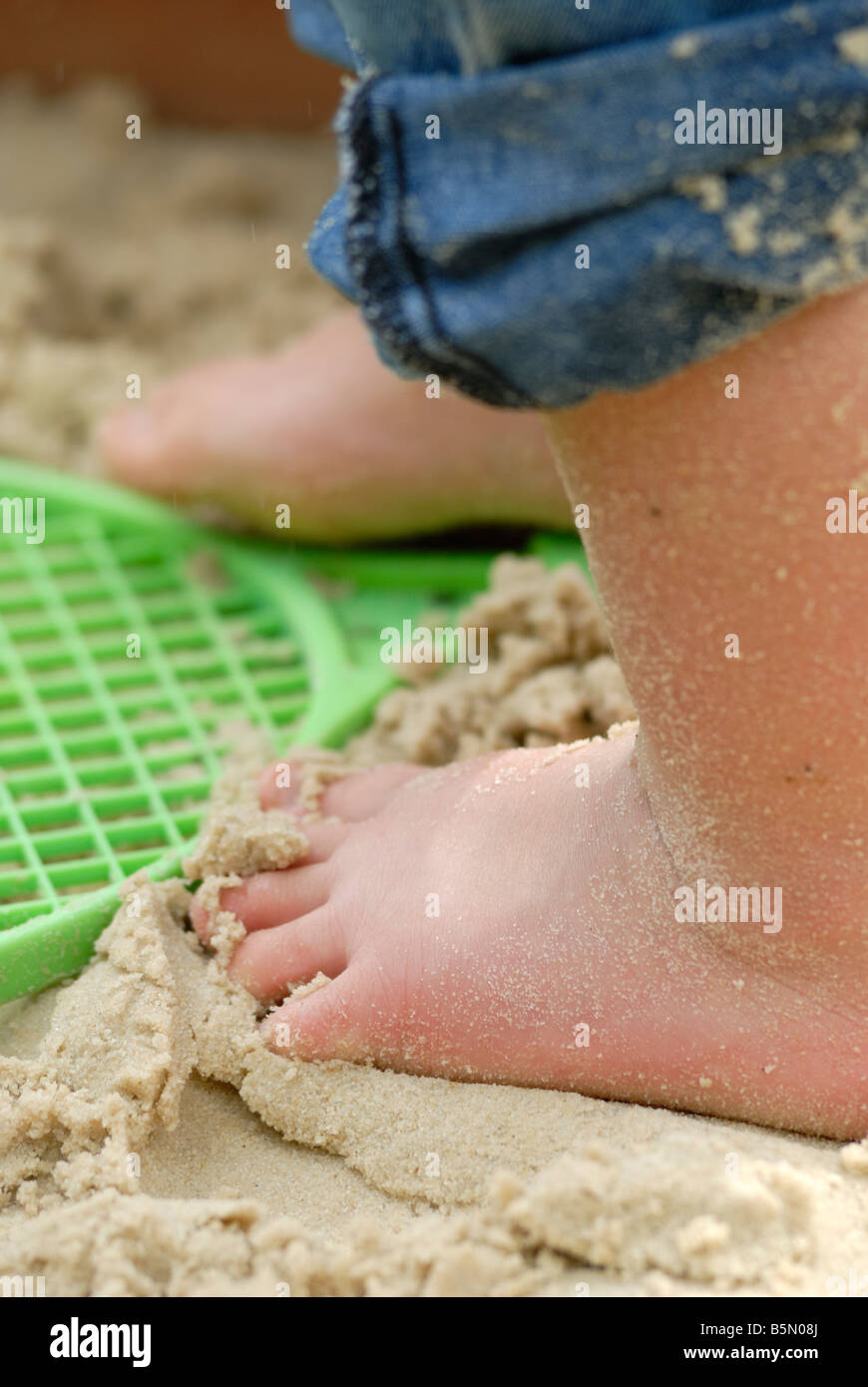 Piccolo Ragazzo in piedi in una buca di sabbia Foto Stock