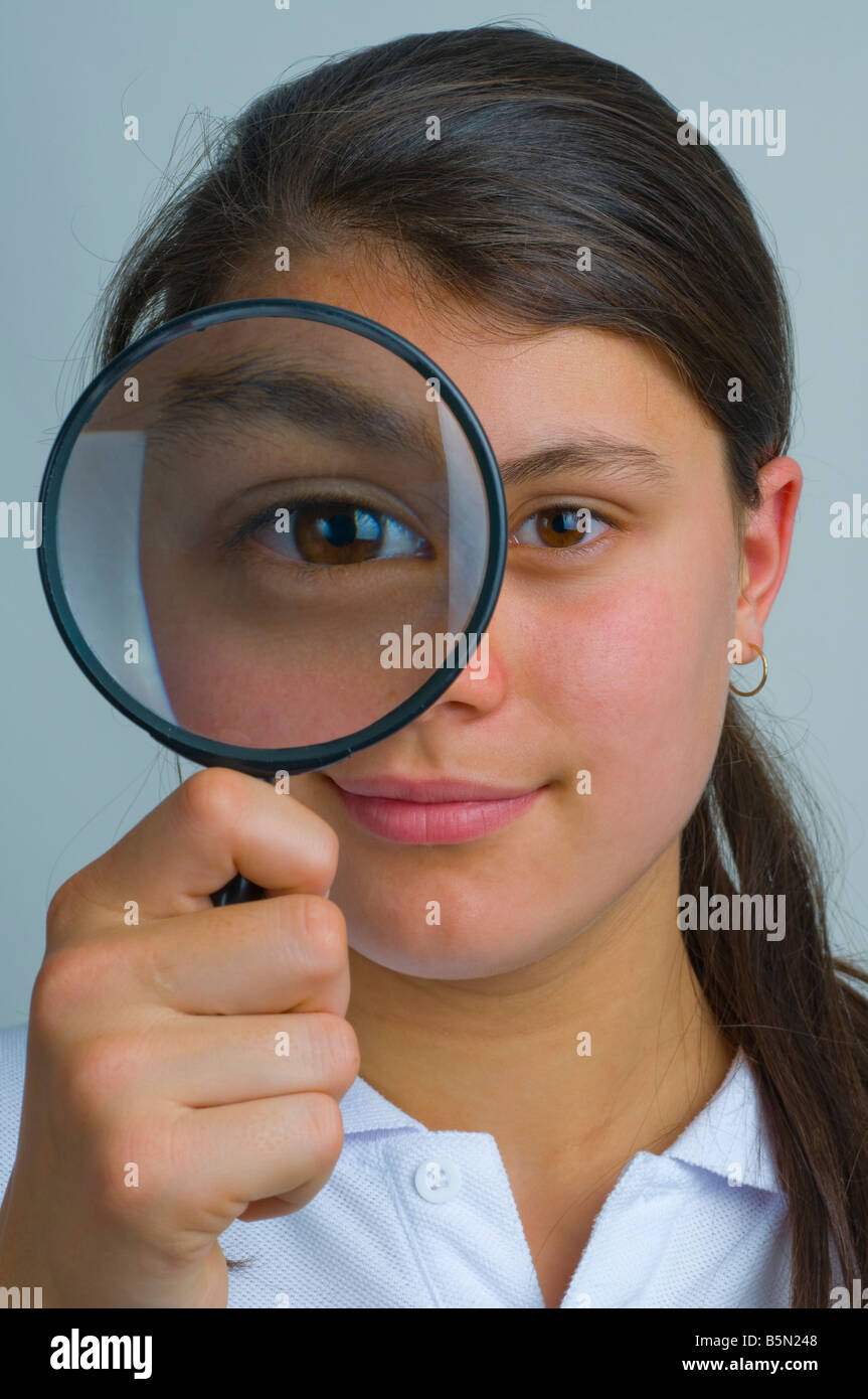 Adolescente guardando attraverso una lente di ingrandimento Foto Stock