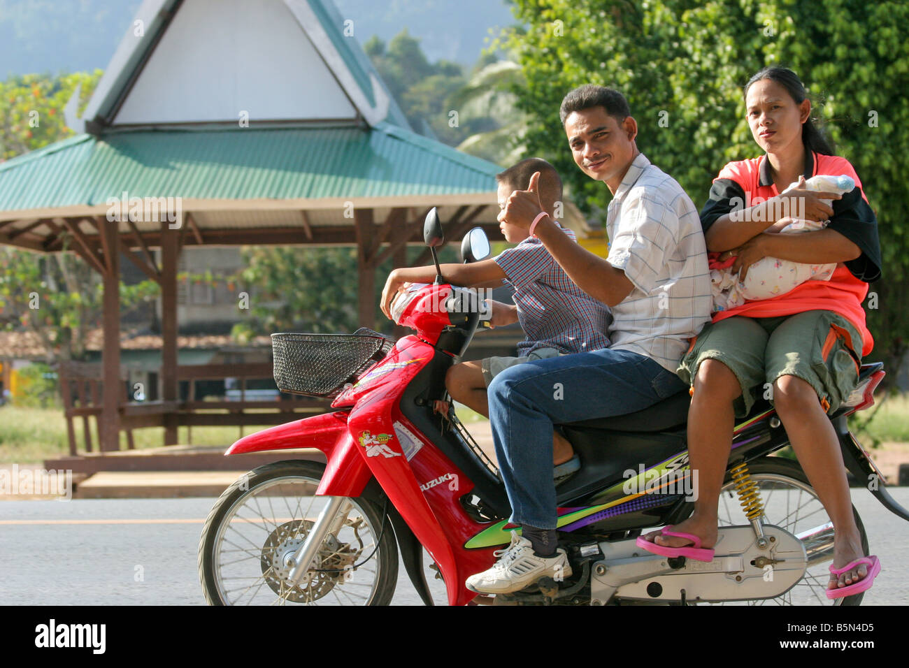 Felice e sorridente famiglia thai riding motociclo, Khao Sok, Thailandia Foto Stock