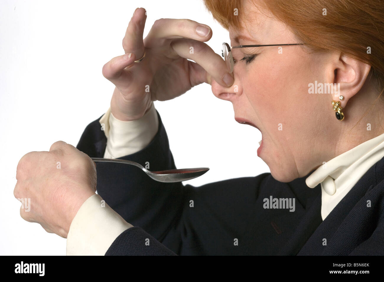 Donna con un cucchiaio di cattiva medicina di degustazione Foto Stock