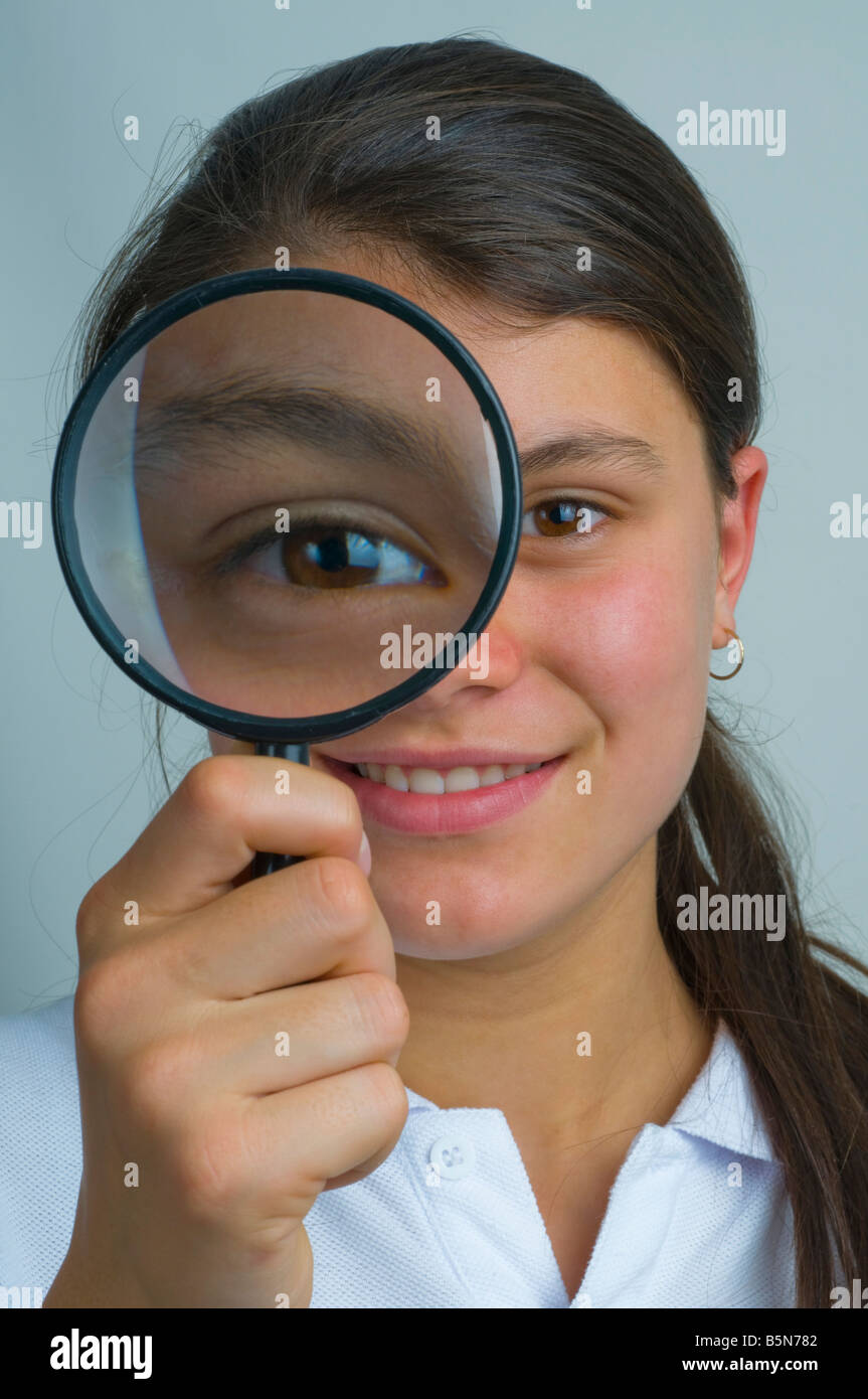 Adolescente guardando attraverso una lente di ingrandimento Foto Stock