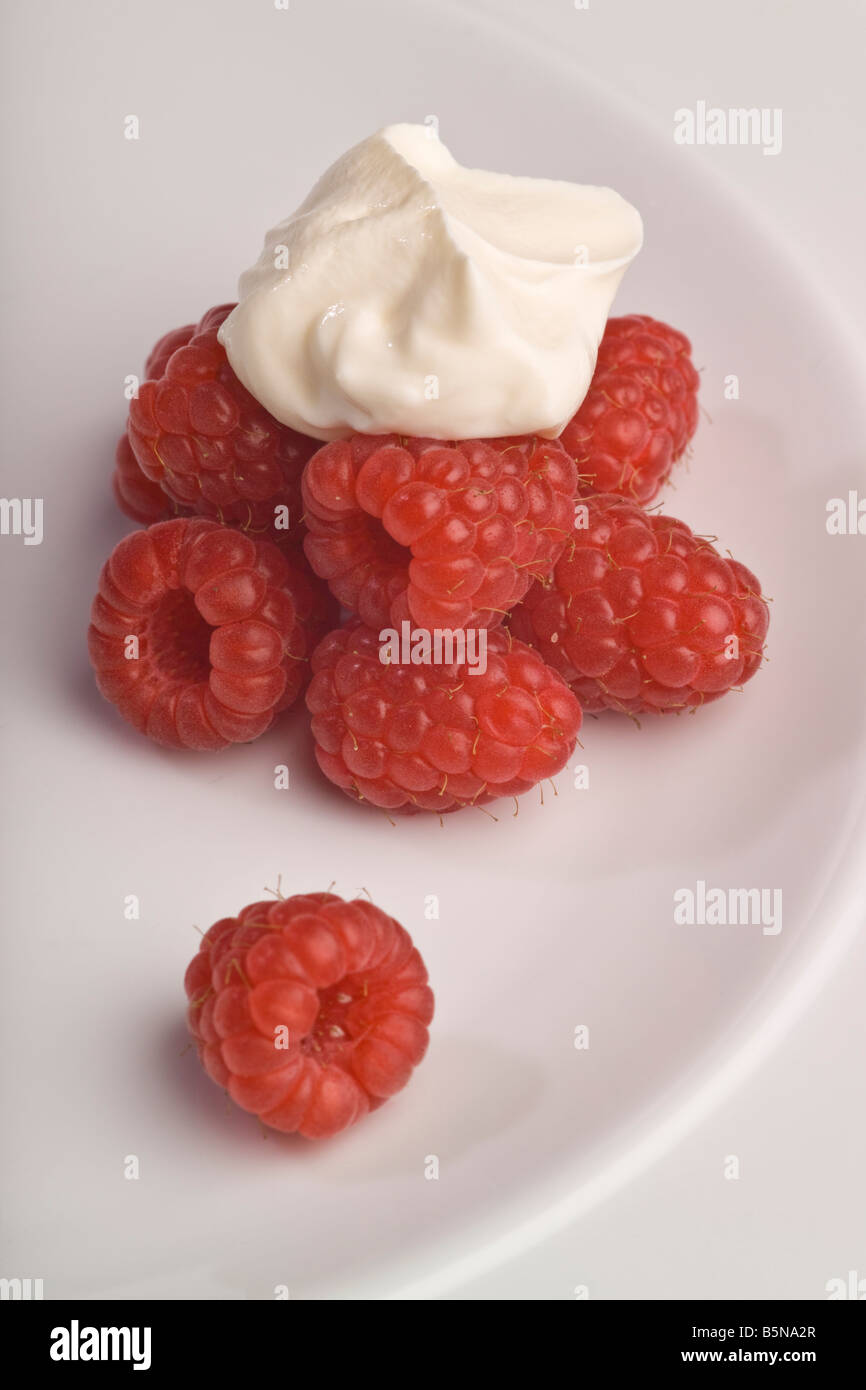 Il lampone e la crema seduto su una piastra bianca Foto Stock