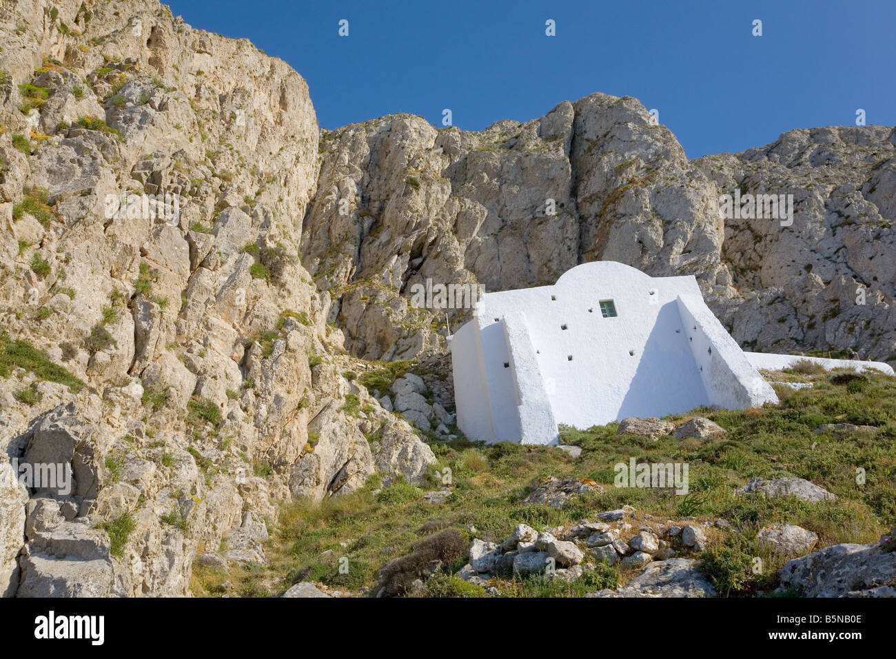 Isolato cappella bianca (Ag.Georgios) sulla ripida parete di roccia di Profitis Ilias montagna di Santorini, Grecia Foto Stock