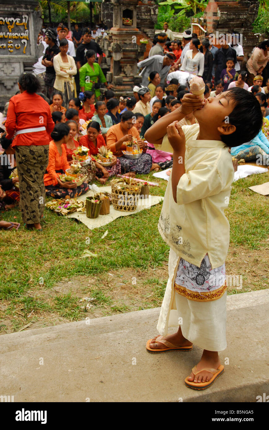 Ragazzo Balinese piace mangiare gelato alla cerimonia di cremazione, Bali, Indonesia Foto Stock
