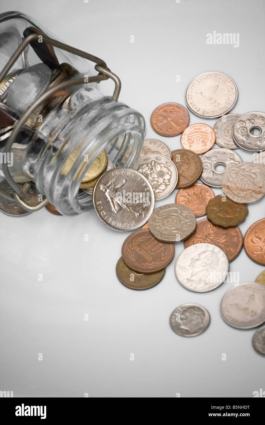 Antico e obsoleto delle monete in euro versato da un contenitore di vetro con sfondo bianco Foto Stock