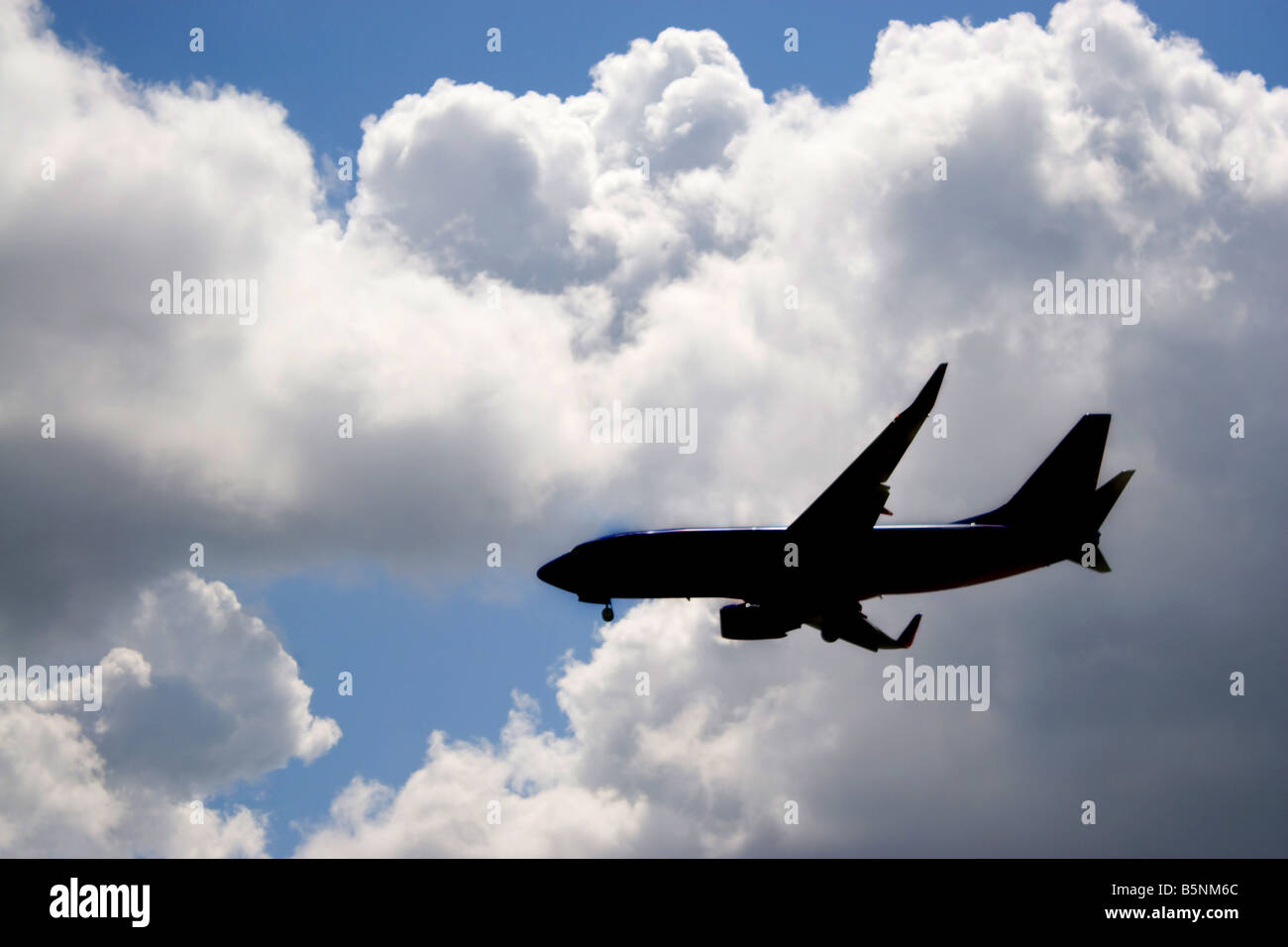 Una silhouette di un passeggero commerciale piano su un cielo blu nella sua discesa a terra Foto Stock
