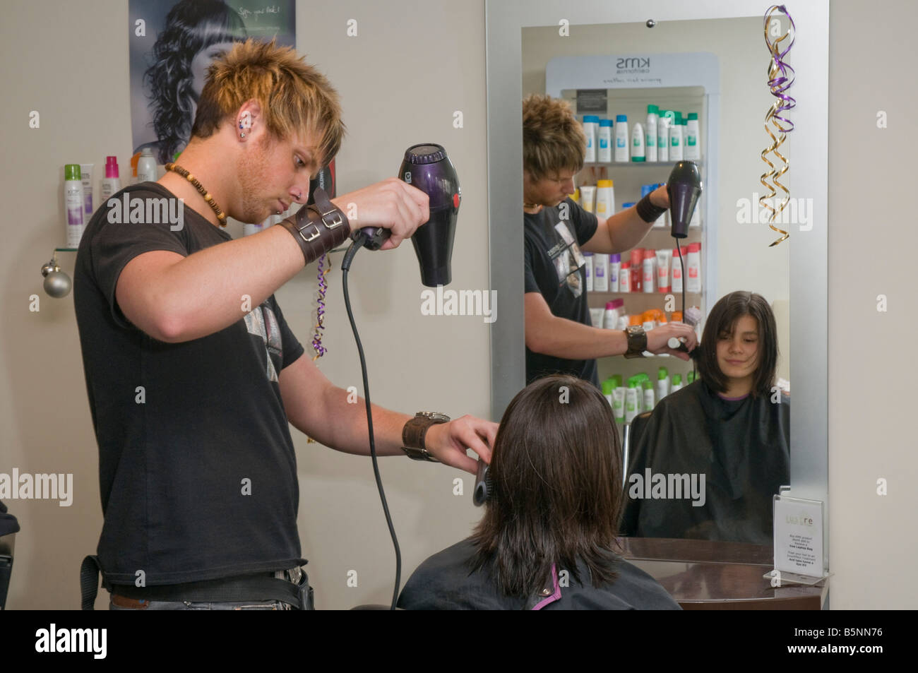 Un adolescente avente i suoi capelli tagliati da un parrucchiere in un salone di parrucchiere Foto Stock
