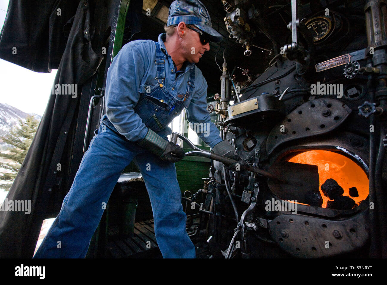 Un vigile del fuoco di badili carbone nella scatola di fuoco di un vapore locomotiva a Durango Silverton Narrow Gauge Railroad Foto Stock