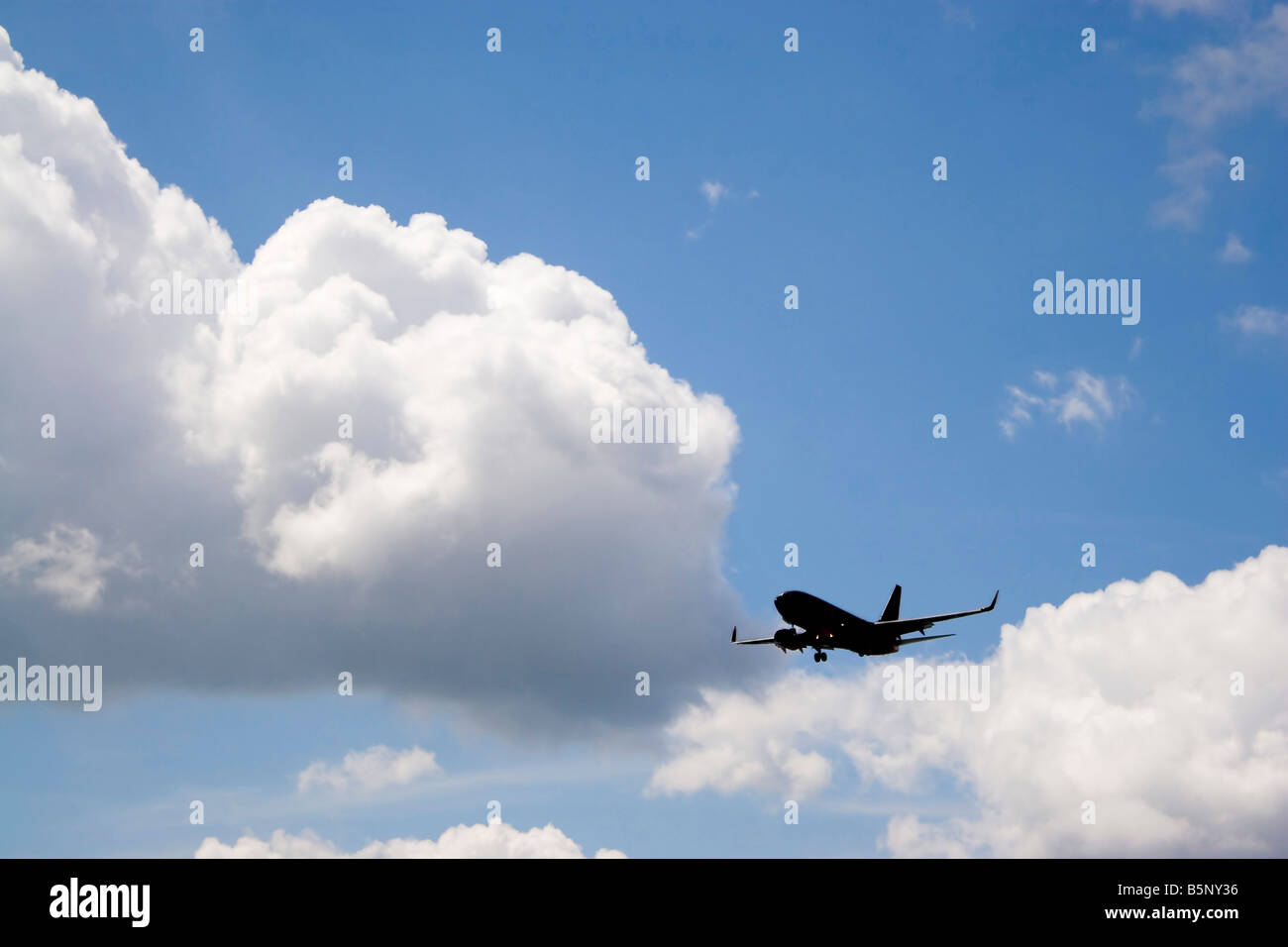 Una silhouette di un passeggero commerciale piano su un cielo blu nella sua discesa a terra Foto Stock
