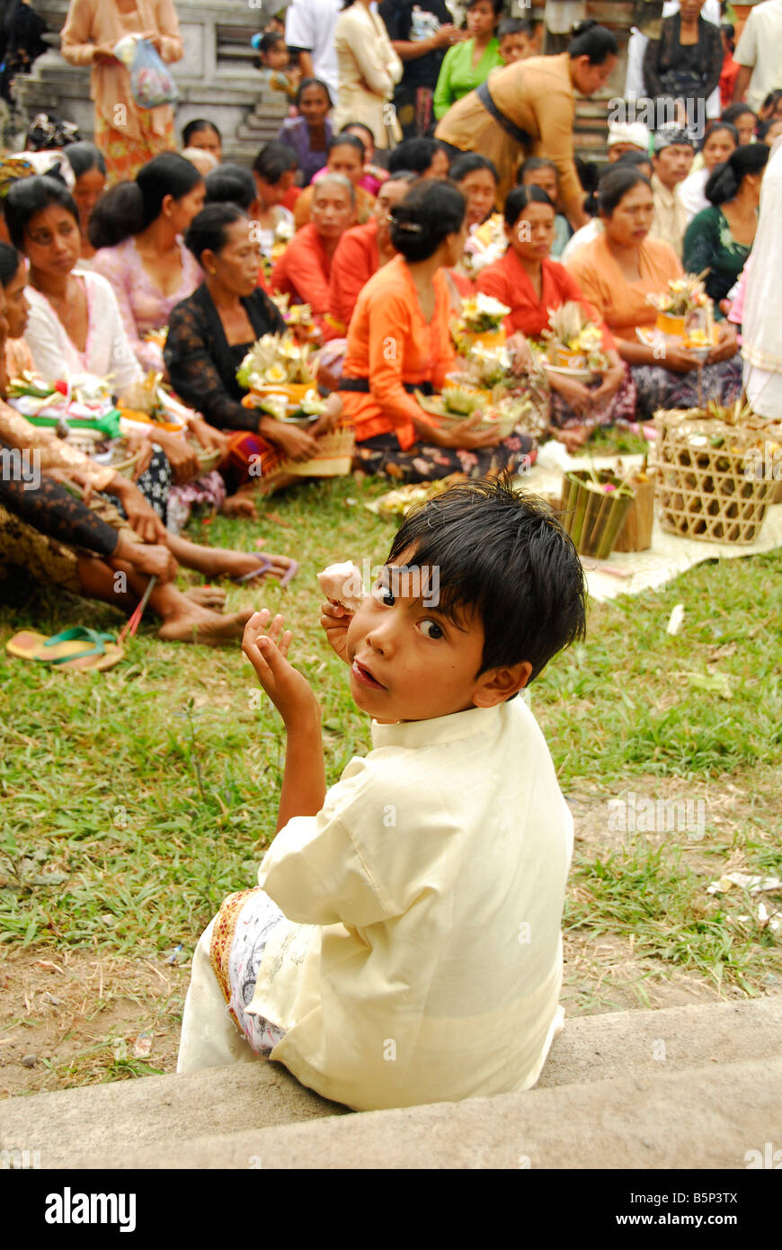 Ragazzo Balinese mangiare gelato alla cerimonia di cremazione,Bali, Indonesia Foto Stock
