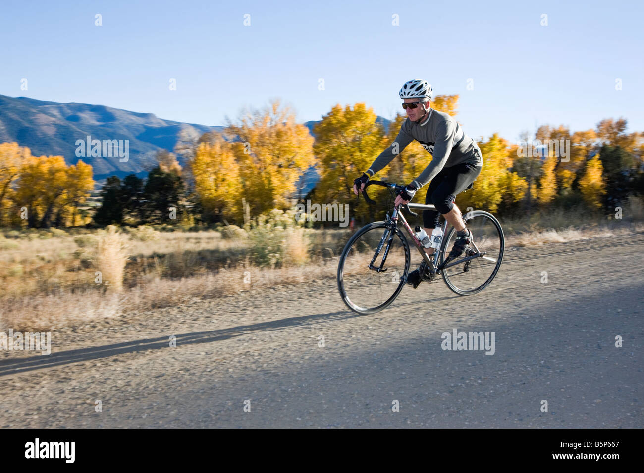 Ciclista maschio cavalcare giù un rurale strada di ghiaia nei pressi di salida, Colorado, STATI UNITI D'AMERICA Foto Stock