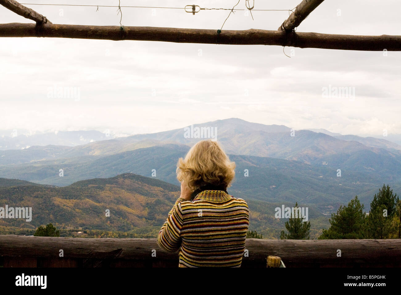 Una giovane donna si affaccia da una baita di montagna dei pirenei alla vista delle montagne Foto Stock