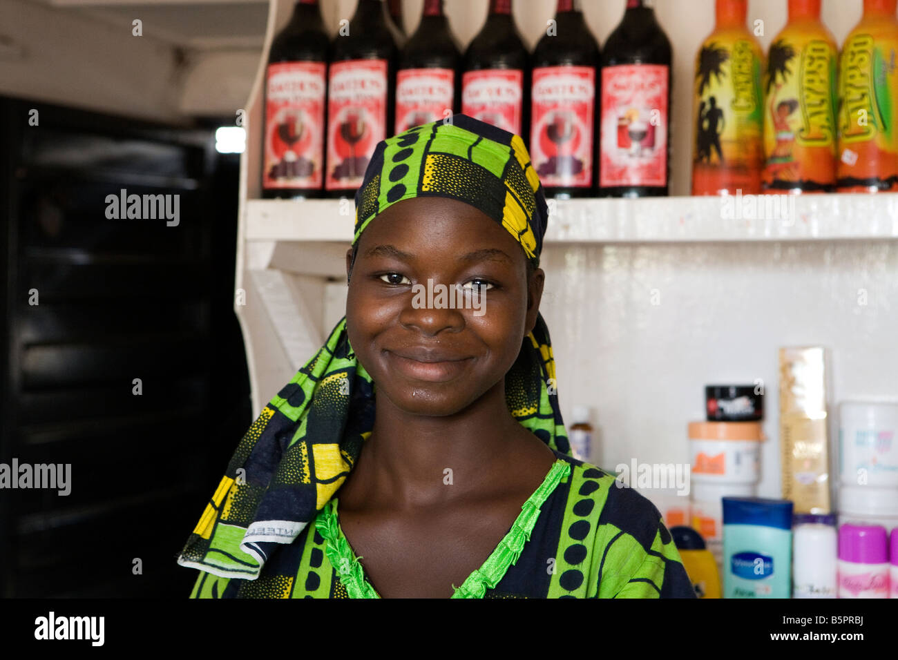 Una donna nigeriana negoziante in posa per una foto di fronte a dei ripiani contenenti la sua mercanzia Foto Stock