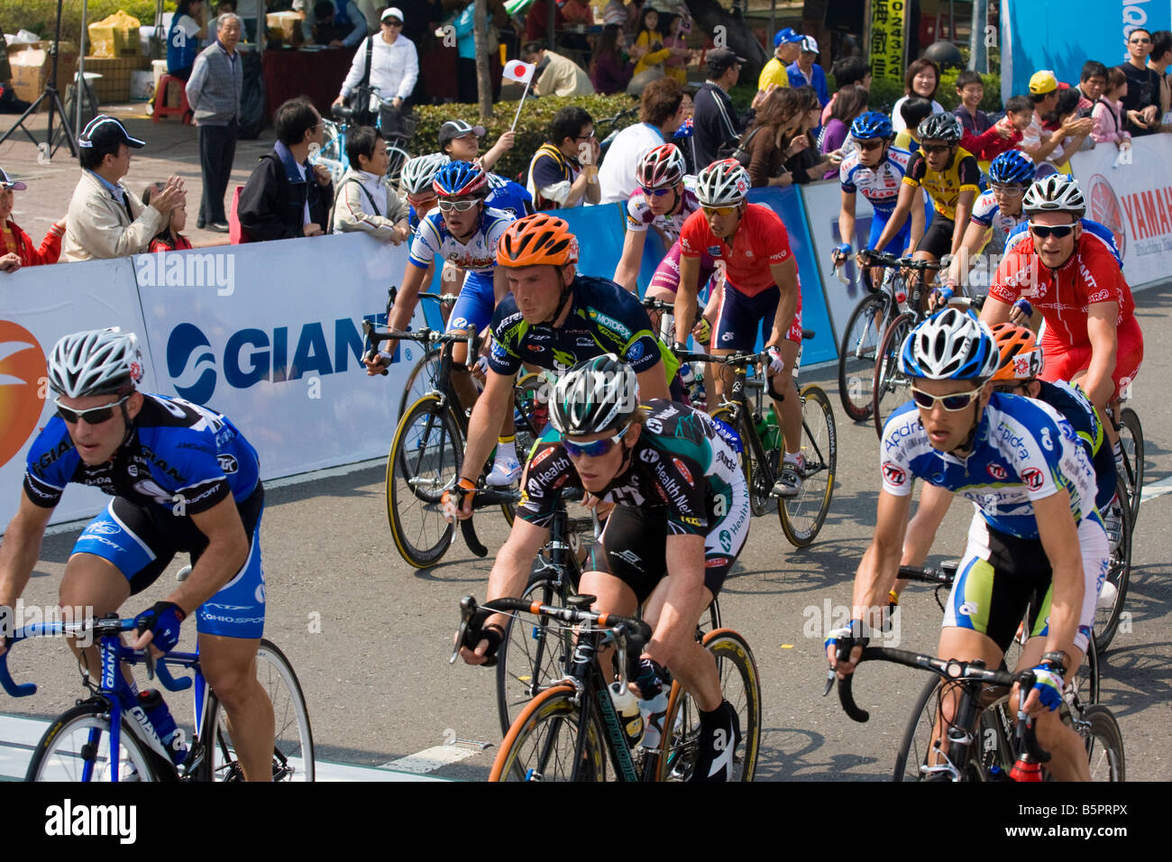 I ciclisti nel peloton ride passato la folla, Tour de Taiwan fase 1 crtierium, Kaohsiung, Taiwan, ROC Foto Stock