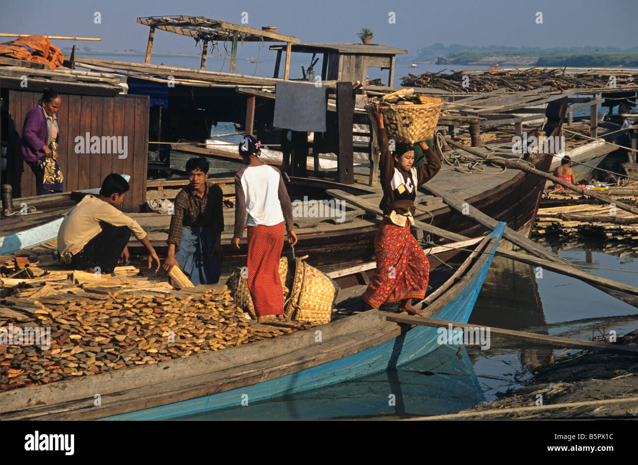 Lo scarico di legna da ardere da una barca sul fiume Irrawaddy al Mandalay Birmania o Myanmar Foto Stock