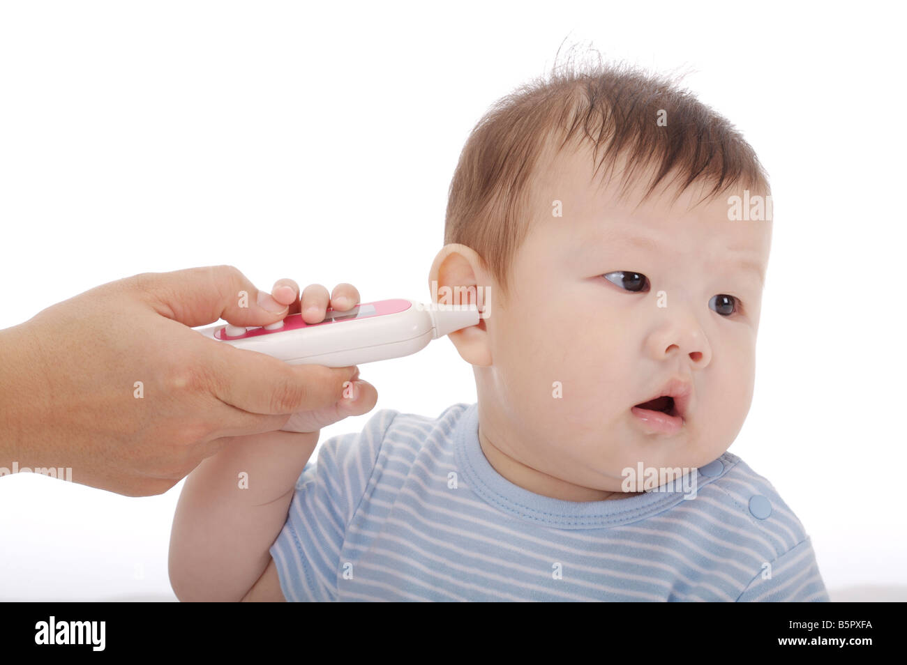 Madre la misurazione della temperatura auricolare di un bambino con un termometro Foto Stock