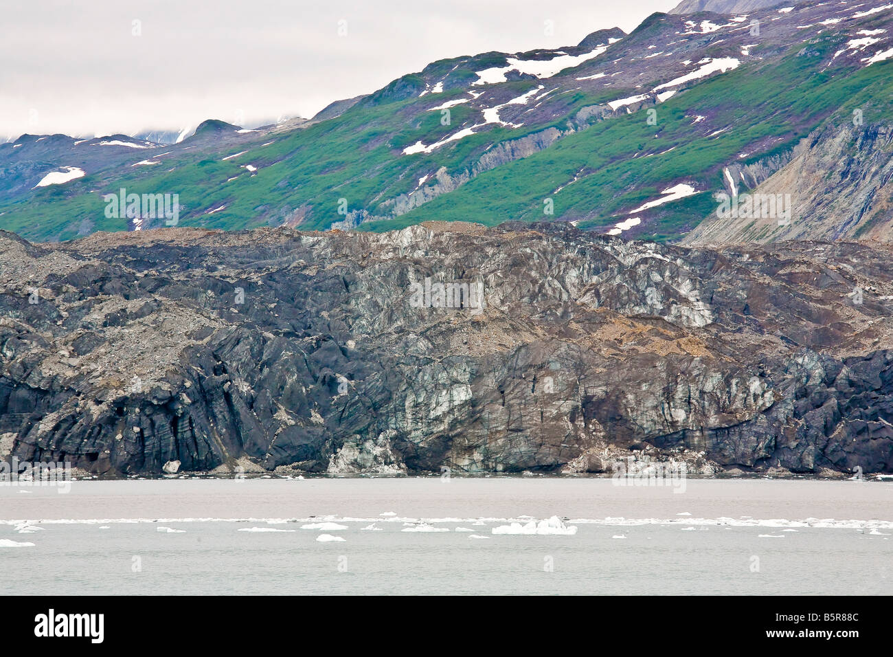 Rock coperta Grand Pacific Glacier un ghiacciaio tidewater all'estremità settentrionale del Parco Nazionale di Glacier Bay AK Foto Stock