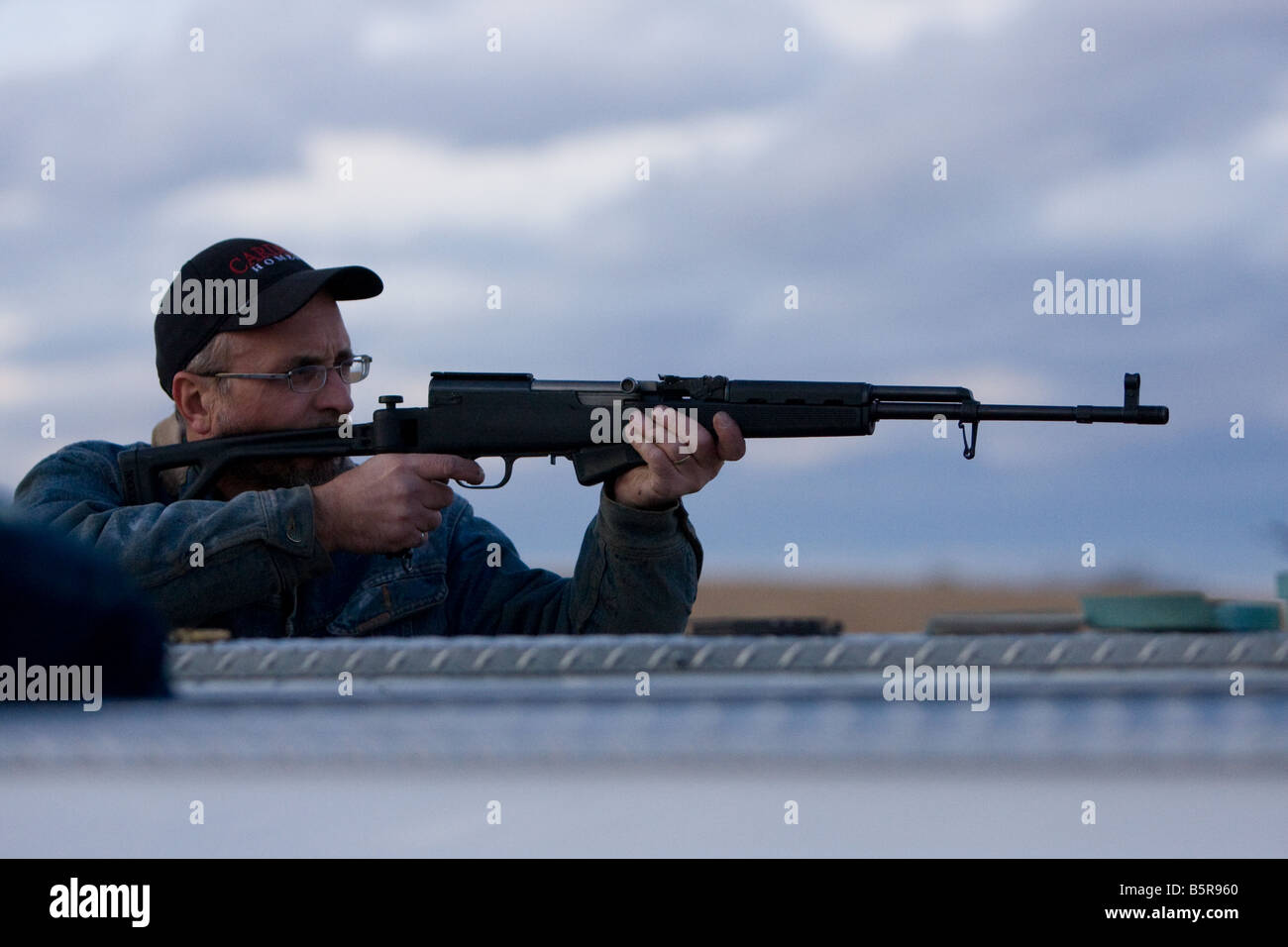 L'uomo la ripresa di un fucile semiautomatico al di fuori della parte posteriore di un camion. Foto Stock