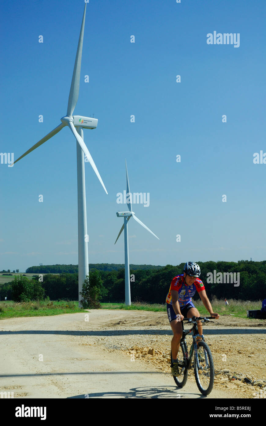 Un ciclista in prossimità di due windturbines di wind farm - Francia Foto Stock