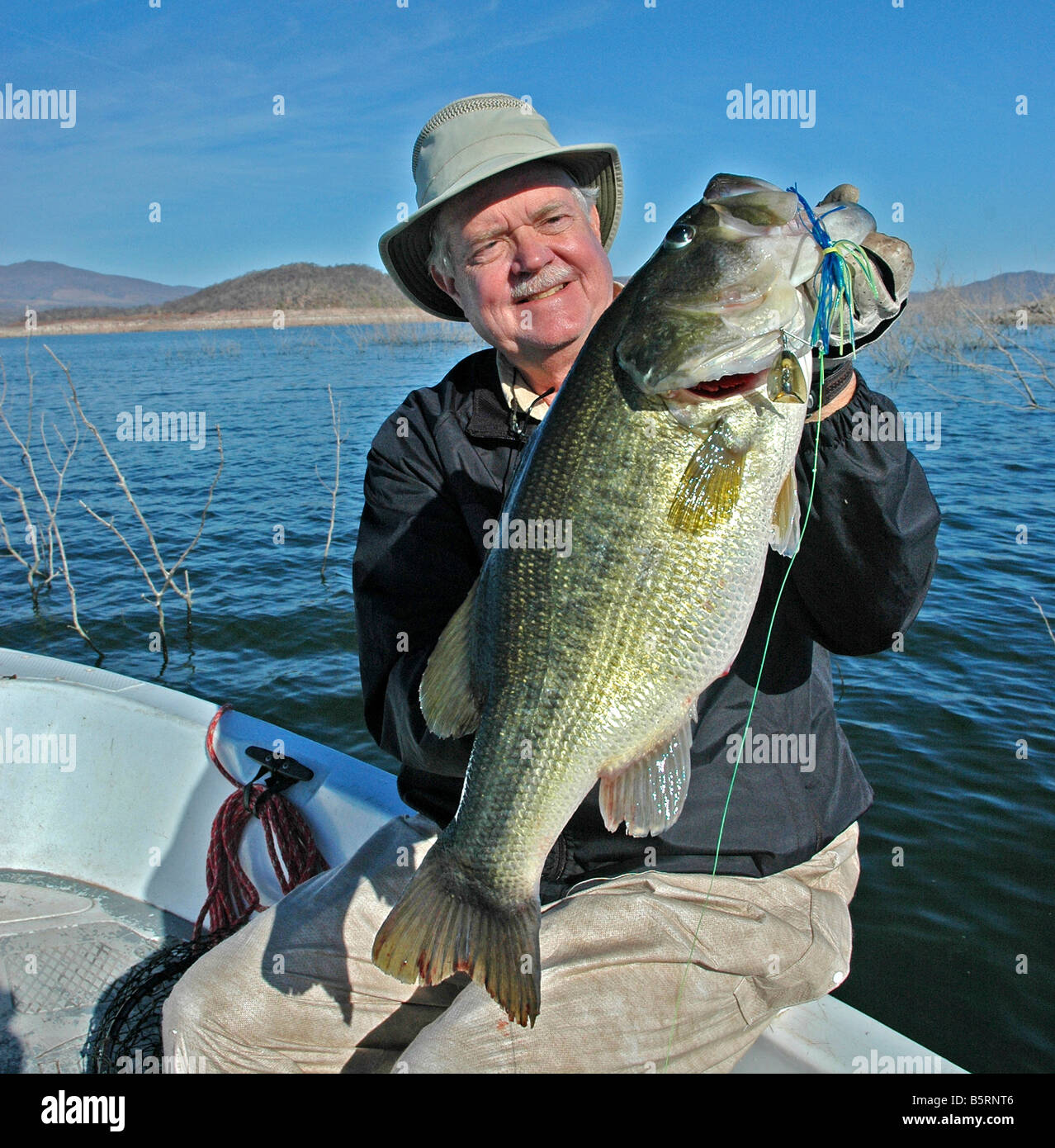 Un bass angler hefts un largemouth catturati da Mesquite stickups sul lago Mateos, un serbatoio messicano nella Sierra Madre Mountains Foto Stock