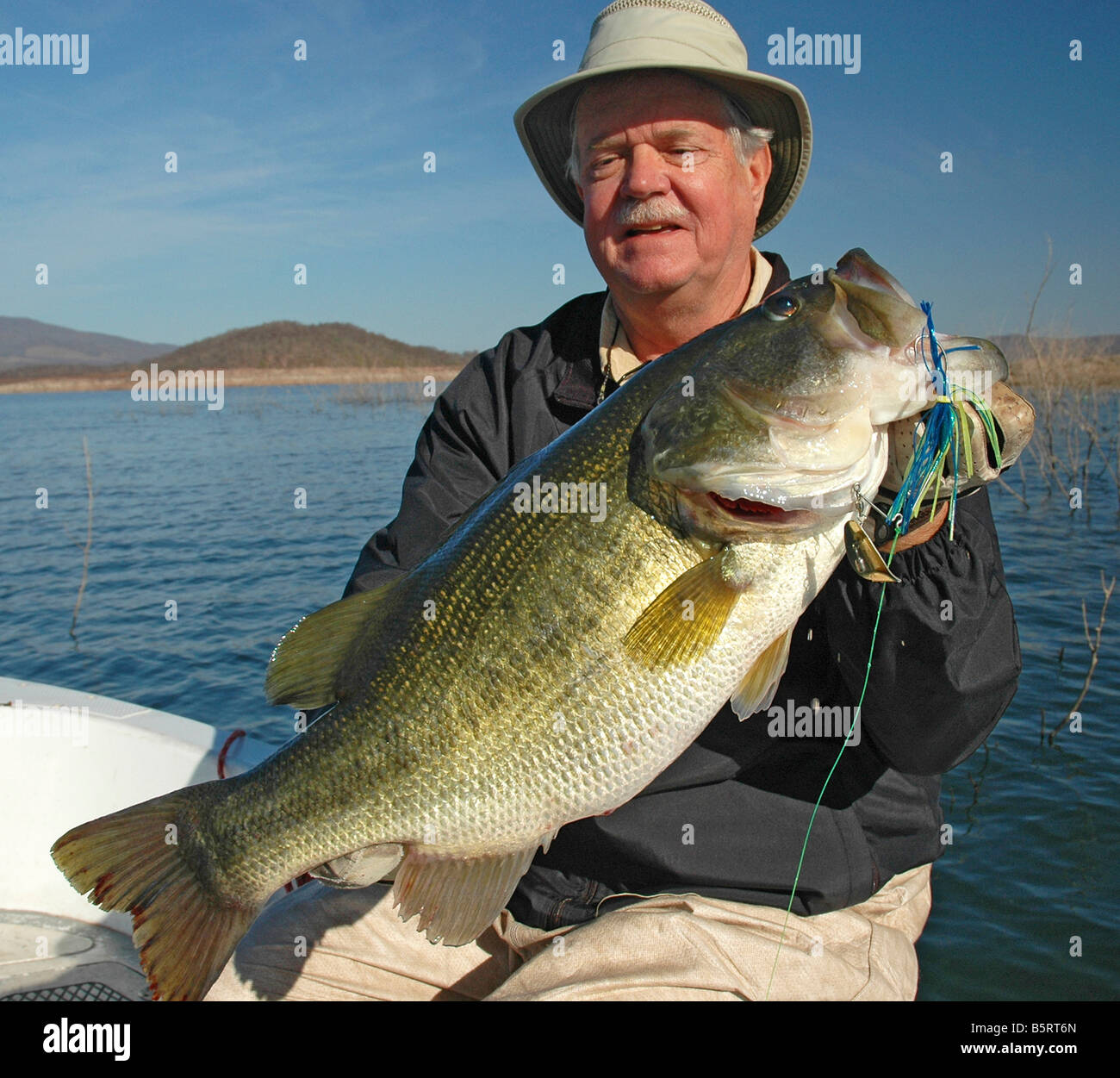 Un bass angler hefts un largemouth catturati su una spinnerbait nel lago Mateos, un serbatoio messicano nella Sierra Madre Mountains. Foto Stock