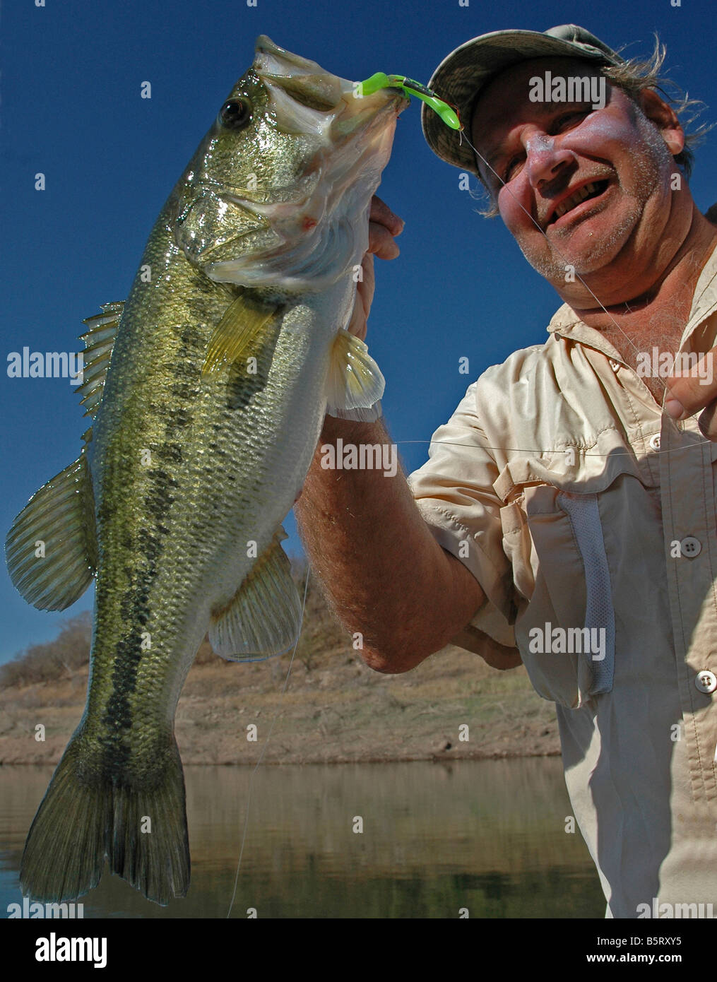 Un bass angler hefts un largemouth catturati su una vite senza fine di plastica nel lago Mateos, un serbatoio messicano nella Sierra Madre Mountains. Foto Stock