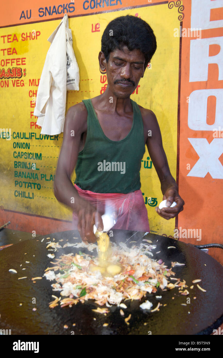Uomo del sud di cucina in stile indiano uova strapazzate in corrispondenza di un bordo strada dhaba di Pondicherry India. Foto Stock