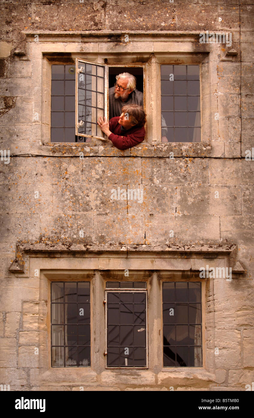 Un paio di ispezionare i loro diciassettesimo secolo Windows su una casa colonica del Costwold con una caratteristica pietra intagliata gocciolare SAPERE COME WEA Foto Stock