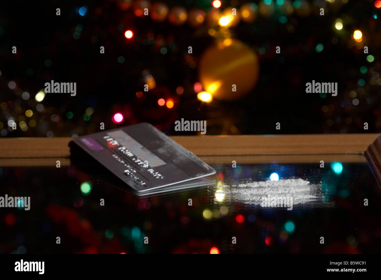 Platinum credit card con linee di cocaina simulato su uno specchio di fronte ad albero di natale Foto Stock