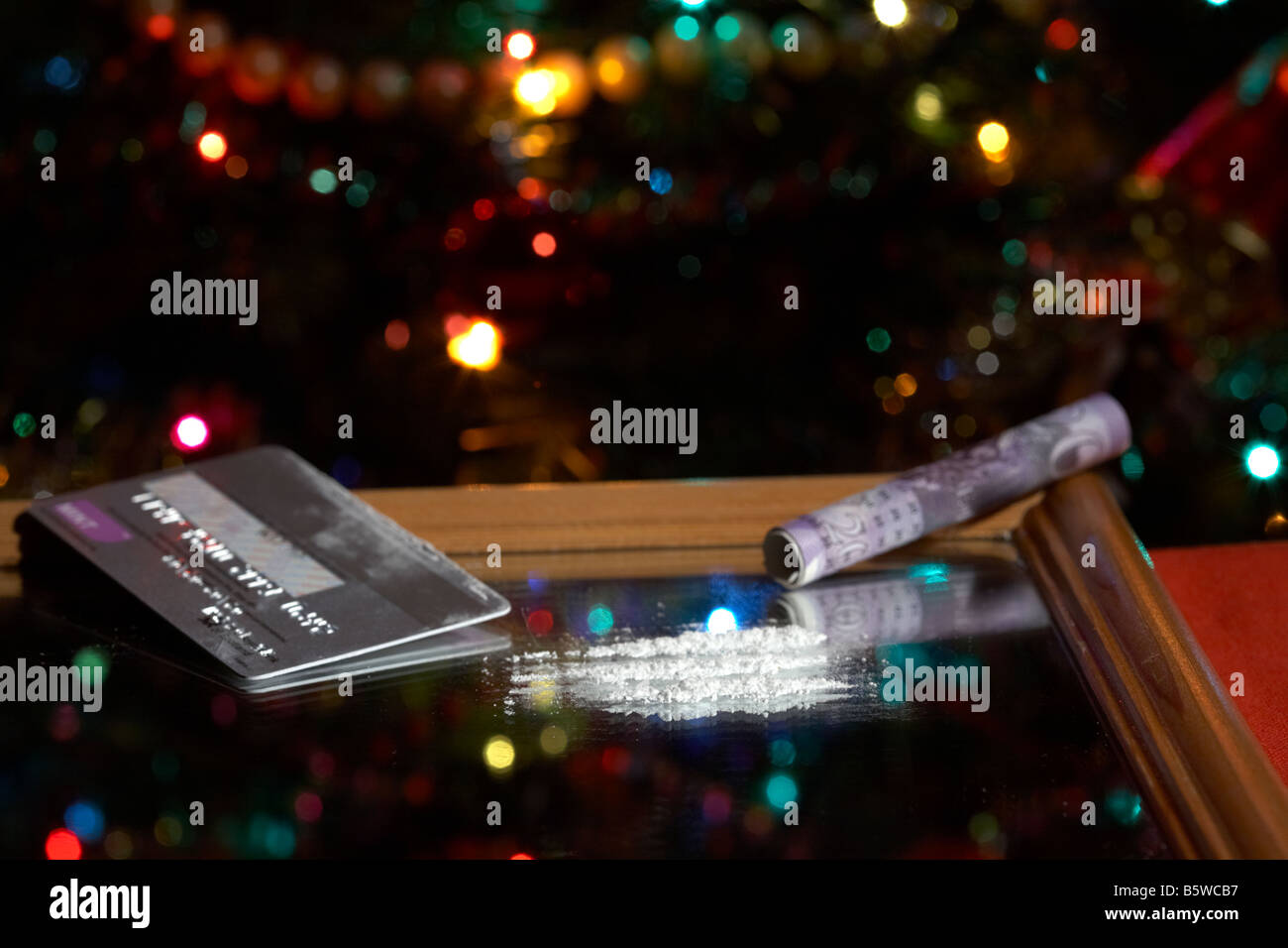 Linee di cocaina simulato su specchio con arrotolato venti sterline contanti nota con platino carta di credito albero di natale Foto Stock