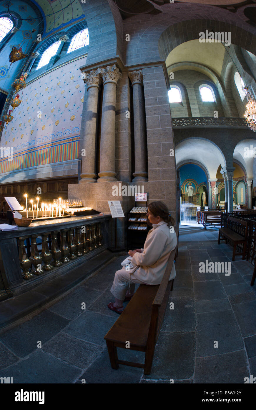 Una donna si siede in silenziosa preghiera davanti all altare, Cattedrale de Notre Dame du Puy Foto Stock