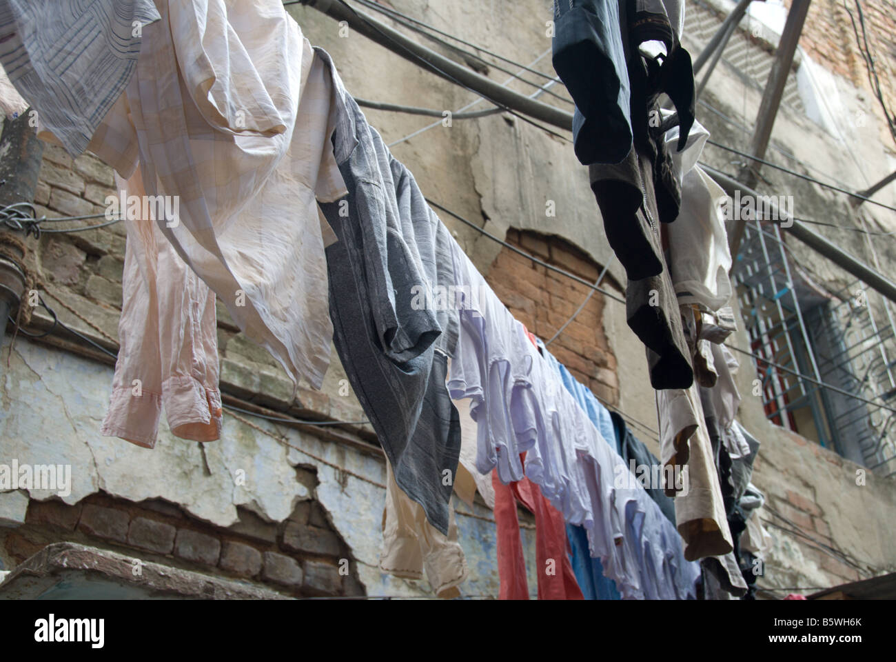 Righe di panni appesi ad asciugare su un tratteggio incrociato di fili e corde attraverso un vicoletto a Nuova Delhi in India. Foto Stock
