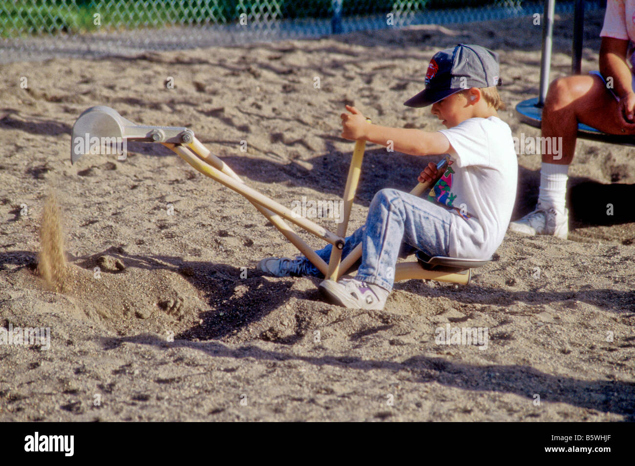 Ragazzo gioca con la sabbia giocattolo digger in city park parco giochi Foto Stock