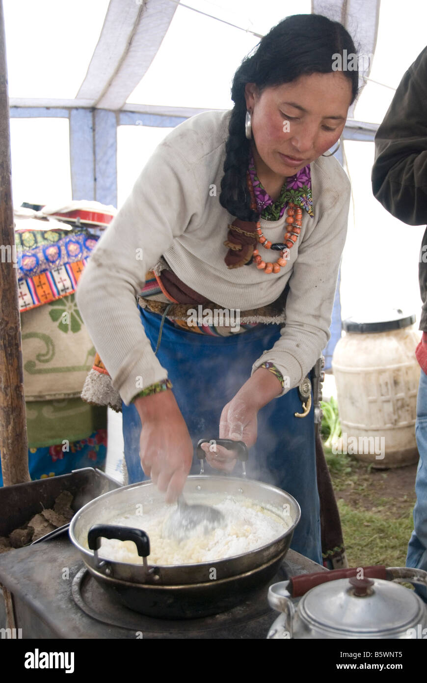 Nomadi donna tibetana la cottura nella sua tenda. Praterie, Sichuan, in Cina. Foto Stock