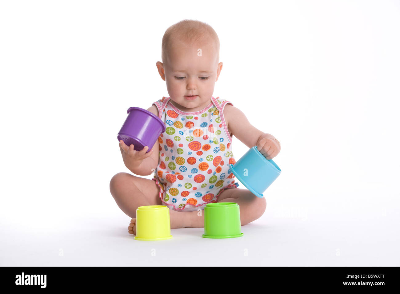 Baby girl giocando con tazze colorate Foto Stock