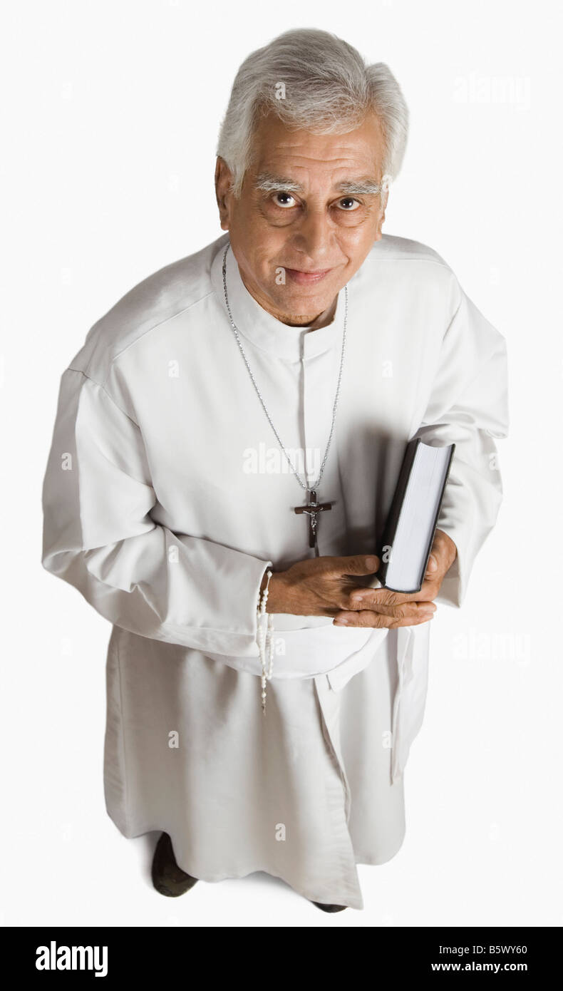 Ritratto di un sacerdote tenendo la Bibbia e sorridente Foto Stock