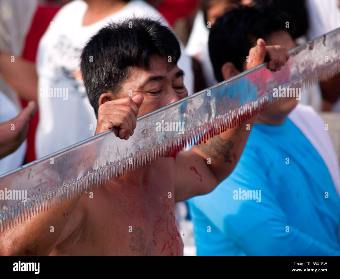 L'uomo segare la sua sanguinosa linguetta al bizzarro Festival vegetariano di Phuket Thailandia Foto Stock