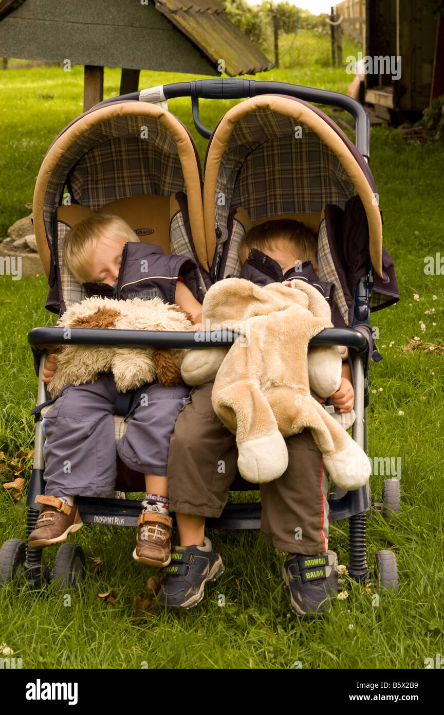 Due fratelli germani addormentato nel loro passeggino con il loro giocattolo cani Foto Stock