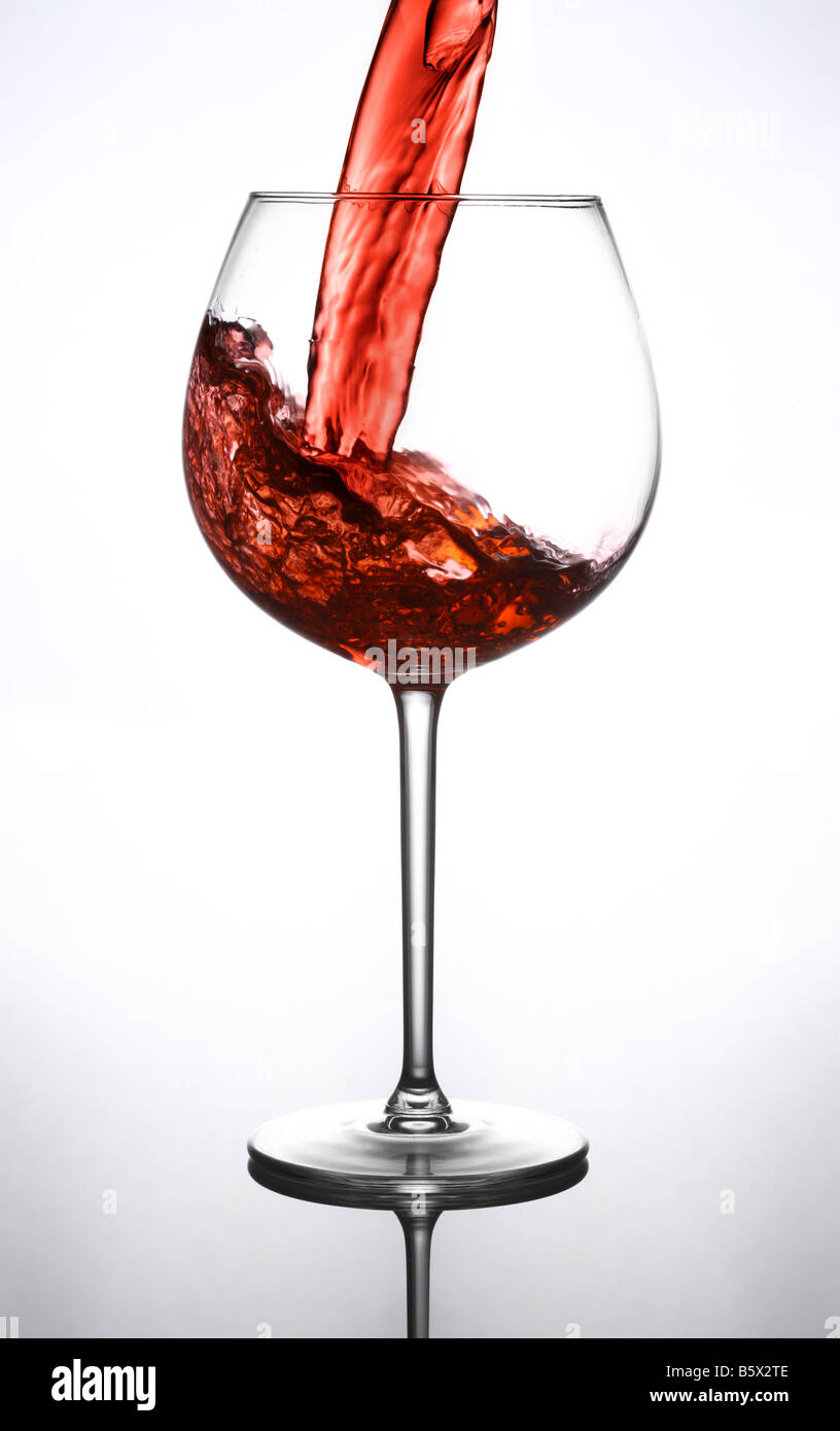 Versando un bicchiere di vino rosso Foto Stock
