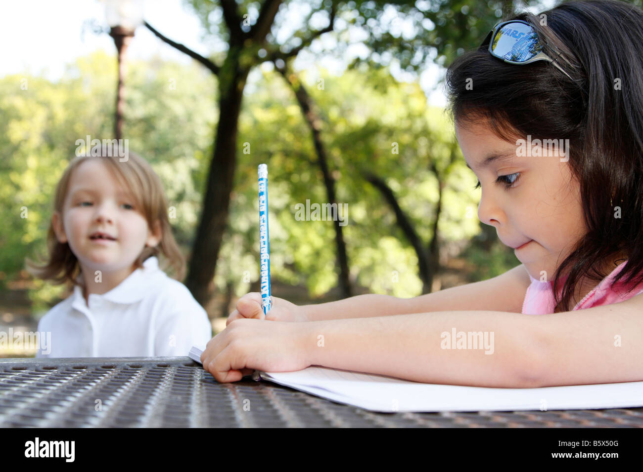 Una giovane ragazza illecite scrivendo la ABC s mentre un altro orologi da una distanza Foto Stock
